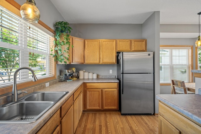 1358 Phalen Blvd, Saint Paul, MN 55106 - kitchen with freestanding refrigerator, light wood-style floors, hanging light fixtures, and light countertops