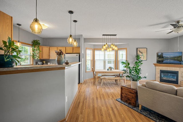 1358 Phalen Blvd, Saint Paul, MN 55106 - living area with light wood-type flooring, a tile fireplace, a ceiling fan, a textured ceiling, and a chandelier