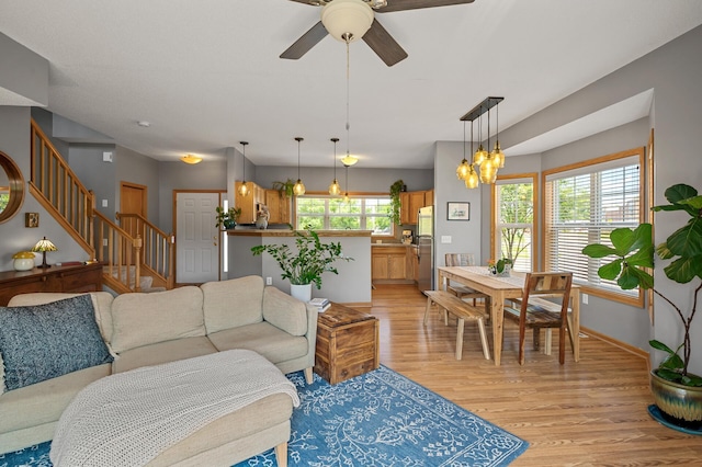 1358 Phalen Blvd, Saint Paul, MN 55106 - living room with light wood-type flooring, stairs, a ceiling fan, and a chandelier