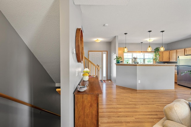 1358 Phalen Blvd, Saint Paul, MN 55106 - kitchen featuring freestanding refrigerator, light wood-type flooring, hanging light fixtures, open floor plan, and a peninsula