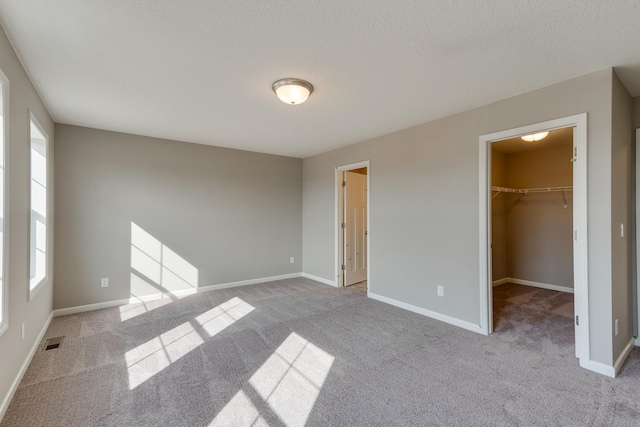 625 47th Ave NE, Saint Cloud, MN 56304 - unfurnished bedroom with carpet flooring, a walk in closet, and a textured ceiling