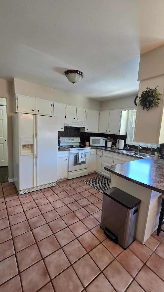 1515 3rd Ave NE, Owatonna, MN 55060 - kitchen with white appliances, dark countertops, under cabinet range hood, white cabinets, and backsplash