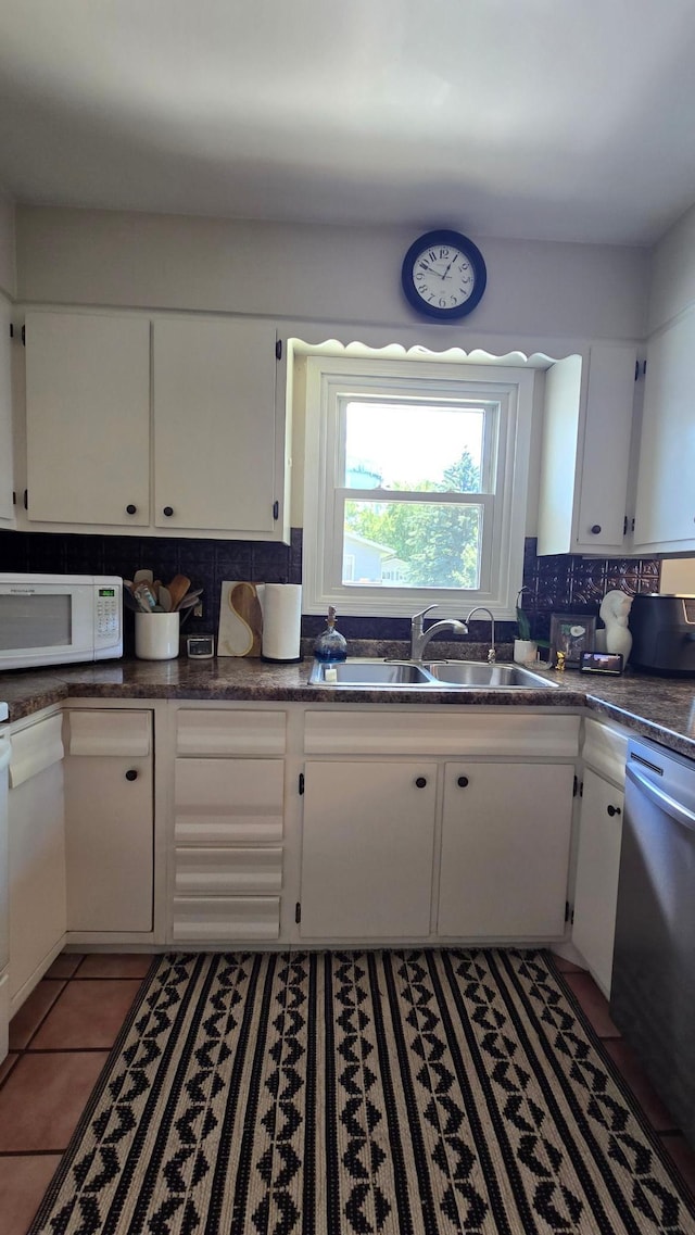 1515 3rd Ave NE, Owatonna, MN 55060 - kitchen featuring white microwave, stainless steel dishwasher, white cabinets, and tasteful backsplash