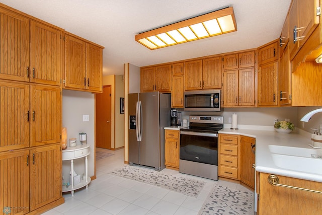 2902 24th Ave S, Fargo, ND 58103 - kitchen featuring appliances with stainless steel finishes, light countertops, brown cabinetry, and light tile patterned floors