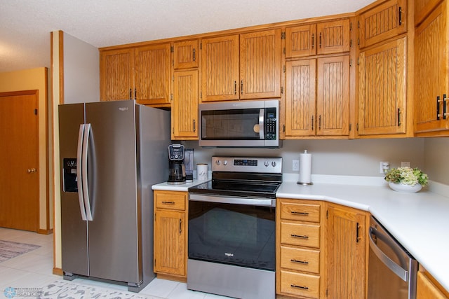 2902 24th Ave S, Fargo, ND 58103 - kitchen featuring appliances with stainless steel finishes, light countertops, light tile patterned flooring, and brown cabinets
