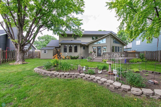 2902 24th Ave S, Fargo, ND 58103 - rear view of house with a storage unit, a fenced backyard, a deck, a vegetable garden, and a shingled roof