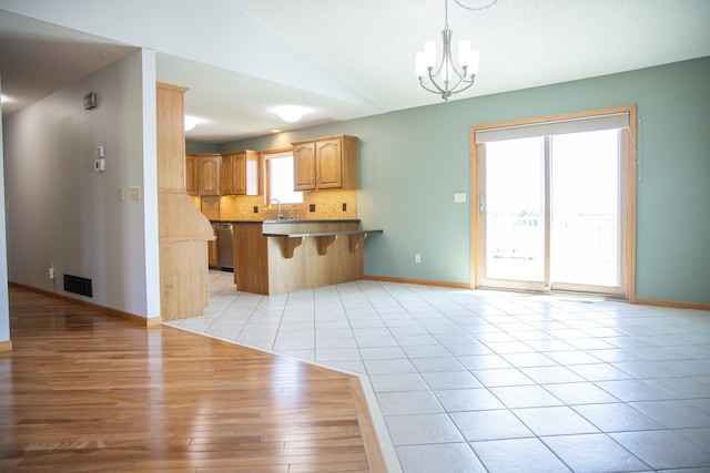 66182 310th Ave, Lake City, MN 55041 - kitchen featuring a chandelier, decorative backsplash, a breakfast bar, a peninsula, and light wood-type flooring