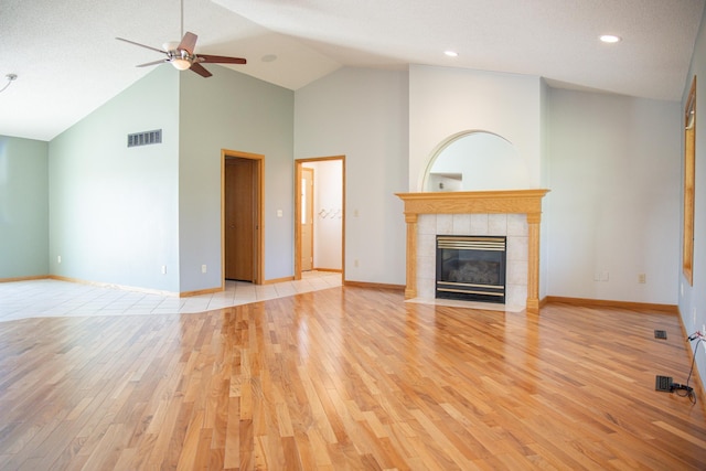 66182 310th Ave, Lake City, MN 55041 - unfurnished living room with light wood finished floors, a ceiling fan, a tile fireplace, high vaulted ceiling, and recessed lighting