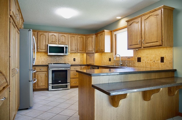 66182 310th Ave, Lake City, MN 55041 - kitchen with appliances with stainless steel finishes, a peninsula, tasteful backsplash, dark countertops, and a textured ceiling