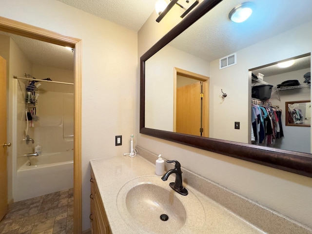 410 Pospeck Ln, Hoyt Lakes, MN 55750 - bathroom with vanity, a textured ceiling, washtub / shower combination, and a spacious closet