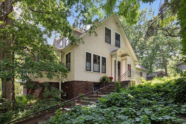 73 Arthur Ave SE, Minneapolis, MN 55414 - view of front of property featuring stairway, stucco siding, brick siding, and a balcony