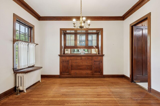 73 Arthur Ave SE, Minneapolis, MN 55414 - unfurnished dining area with radiator, crown molding, a chandelier, and light wood-type flooring
