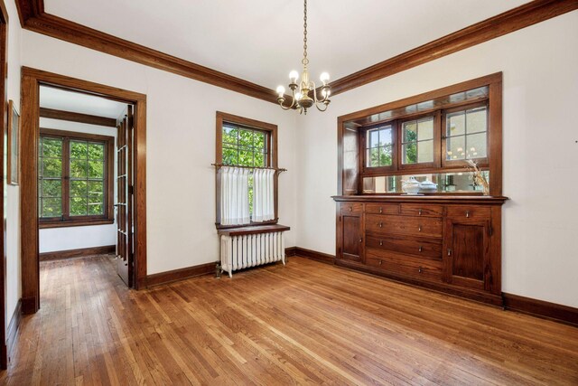 73 Arthur Ave SE, Minneapolis, MN 55414 - unfurnished dining area with radiator, a chandelier, crown molding, healthy amount of natural light, and light wood-type flooring