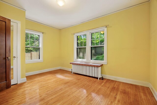 73 Arthur Ave SE, Minneapolis, MN 55414 - unfurnished room featuring radiator heating unit, light wood-style floors, and crown molding