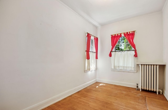 73 Arthur Ave SE, Minneapolis, MN 55414 - spare room featuring radiator heating unit, ornamental molding, and wood finished floors