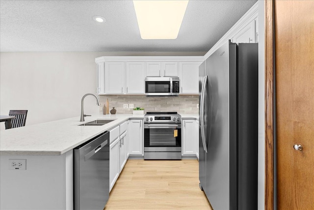 7514 Ojibway Park Rd, Woodbury, MN 55125 - kitchen featuring stainless steel appliances, a peninsula, light wood-type flooring, white cabinetry, and a textured ceiling