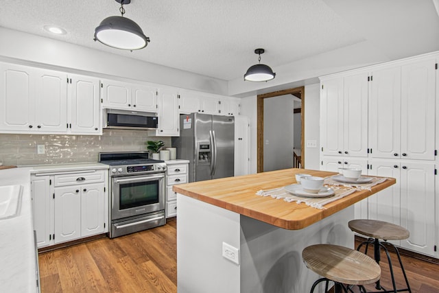 7401 River Shore Ln, Champlin, MN 55316 - kitchen featuring stainless steel appliances, white cabinets, dark wood-style floors, a textured ceiling, and hanging light fixtures