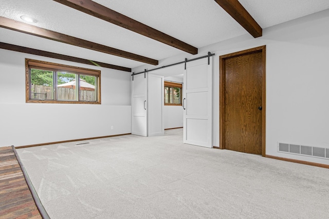 7401 River Shore Ln, Champlin, MN 55316 - spare room with a barn door, plenty of natural light, light colored carpet, and beam ceiling