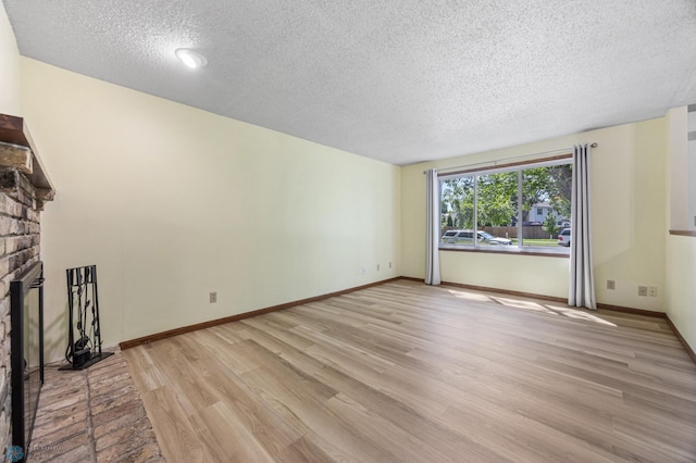 3237 17th Ave S Unit 101, Fargo, ND 58103 - unfurnished living room with a textured ceiling, light wood-type flooring, and a brick fireplace