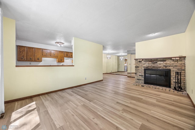 3237 17th Ave S Unit 101, Fargo, ND 58103 - unfurnished living room featuring light wood-style floors, a fireplace, and a textured ceiling