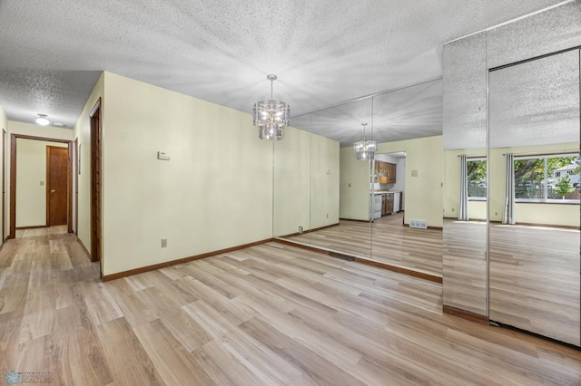 3237 17th Ave S Unit 101, Fargo, ND 58103 - unfurnished living room featuring a chandelier, light wood-style floors, and a textured ceiling