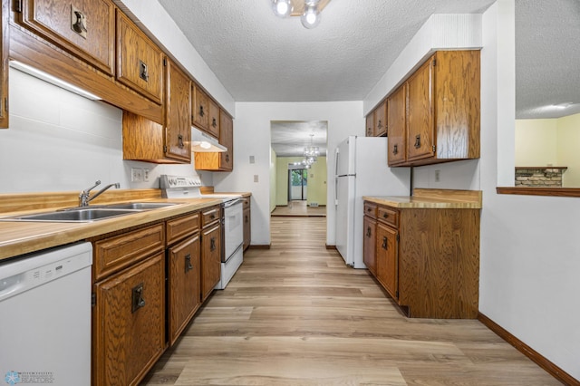 3237 17th Ave S Unit 101, Fargo, ND 58103 - kitchen featuring white appliances, a textured ceiling, under cabinet range hood, light wood-style flooring, and brown cabinets