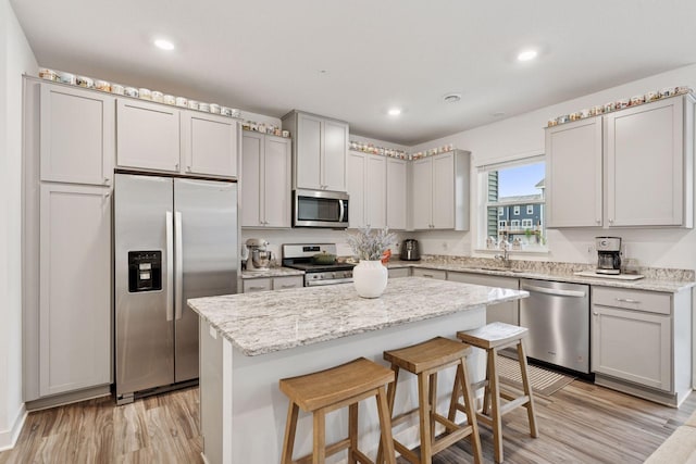 11121 Balsam Pointe Trl, Dayton, MN 55327 - kitchen with stainless steel appliances, light wood-style floors, a center island, a kitchen breakfast bar, and gray cabinetry