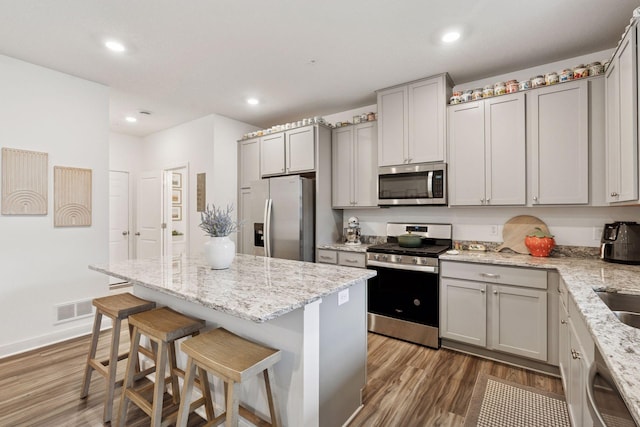11121 Balsam Pointe Trl, Dayton, MN 55327 - kitchen with stainless steel appliances, a breakfast bar, wood finished floors, gray cabinets, and recessed lighting