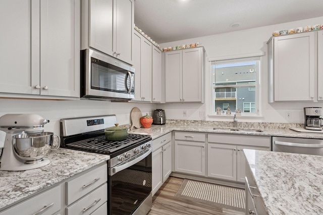 11121 Balsam Pointe Trl, Dayton, MN 55327 - kitchen featuring appliances with stainless steel finishes, light wood-type flooring, and light stone countertops