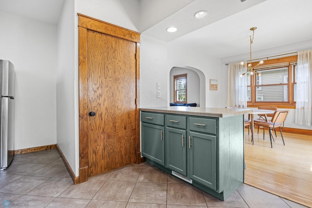 726 Oak St N, Fargo, ND 58102 - kitchen with green cabinetry, arched walkways, a chandelier, freestanding refrigerator, and light countertops