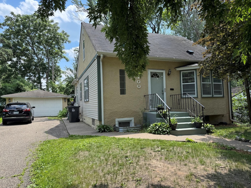 2100 Nortonia Ave, Saint Paul, MN 55119 - view of front of house featuring a detached garage, an outdoor structure, stucco siding, and roof with shingles