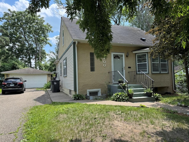 2100 Nortonia Ave, Saint Paul, MN 55119 - view of front of house featuring a detached garage, an outdoor structure, stucco siding, and roof with shingles