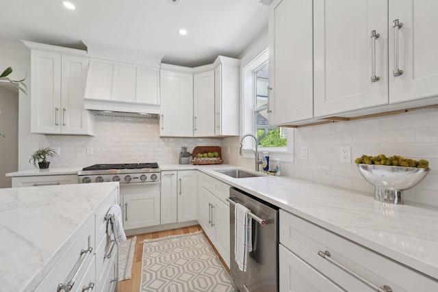 109 Pine St E, Stillwater, MN 55082 - kitchen with appliances with stainless steel finishes, white cabinets, light stone countertops, light wood-style flooring, and decorative backsplash