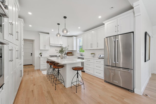 109 Pine St E, Stillwater, MN 55082 - kitchen with stainless steel appliances, a breakfast bar area, light wood finished floors, light countertops, and white cabinets