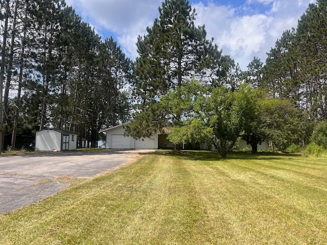 21837 Mishawaka Rd, Grand Rapids, MN 55744 - view of green lawn with driveway, a shed, and a garage