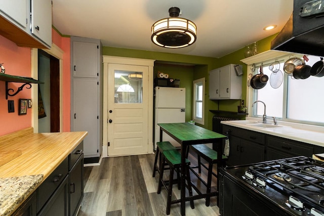 2912 15th Ave S, Minneapolis, MN 55407 - kitchen with freestanding refrigerator, black range with gas cooktop, light countertops, dark wood finished floors, and recessed lighting