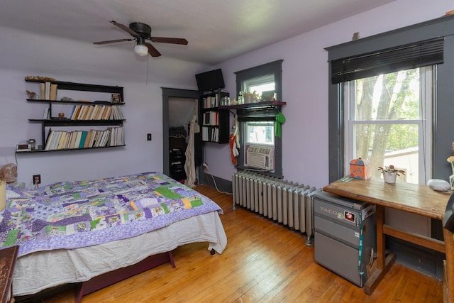 2912 15th Ave S, Minneapolis, MN 55407 - bedroom featuring radiator heating unit, wood-type flooring, cooling unit, and a ceiling fan