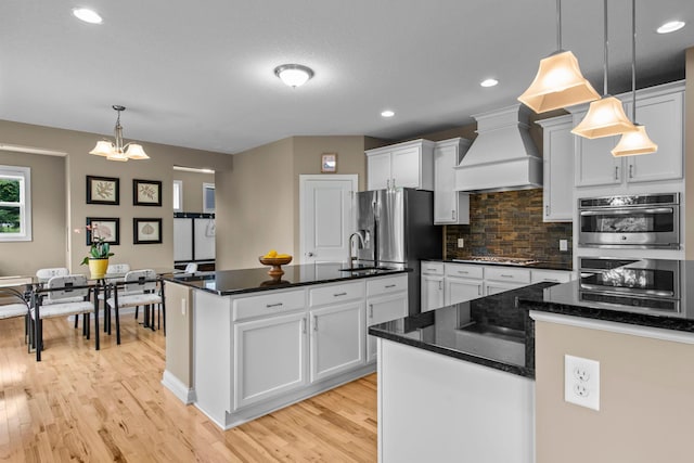 18837 Javelin Way, Lakeville, MN 55044 - kitchen with custom range hood, stainless steel appliances, backsplash, light wood-type flooring, and white cabinetry