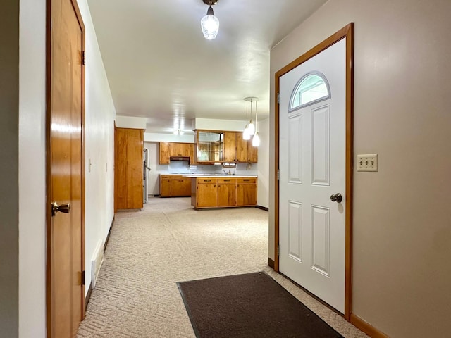 1224 Duba St, Worthington, MN 56187 - kitchen featuring brown cabinets, light colored carpet, light countertops, pendant lighting, and extractor fan
