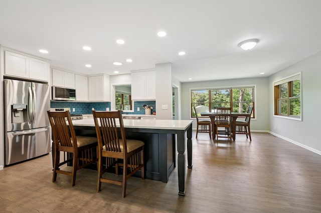 22470 Raven St NW, Oak Grove, MN 55011 - kitchen featuring appliances with stainless steel finishes, light countertops, dark wood finished floors, white cabinetry, and tasteful backsplash