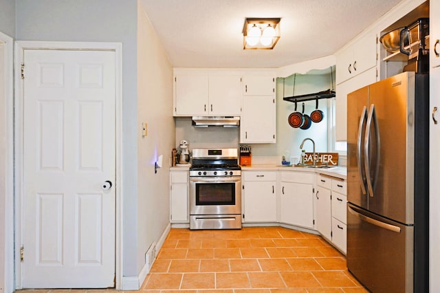 1631 Ross Ave, Saint Paul, MN 55106 - kitchen featuring appliances with stainless steel finishes, under cabinet range hood, white cabinetry, light tile patterned floors, and light countertops