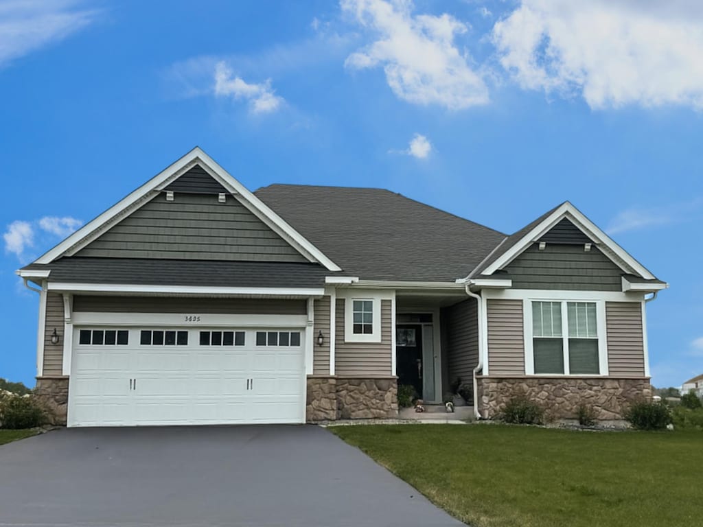 3626 110th Ln NE, Blaine, MN 55449 - craftsman house featuring stone siding, concrete driveway, an attached garage, and a front lawn