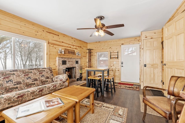 46317 Lucretia Ln, Isle, MN 56342 - living room with healthy amount of natural light, ceiling fan, wood walls, dark wood finished floors, and a fireplace