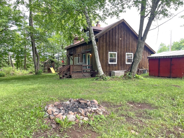 5566 Little Marais Rd, Crystal Bay Twp, MN 55603 - rear view of property with a fire pit, a yard, a wooden deck, a chimney, and a playground