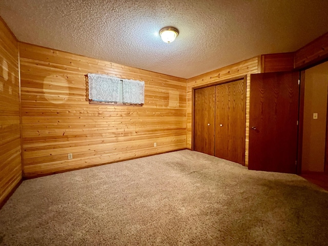 1002 6th Ave N, Wheaton, MN 56296 - unfurnished bedroom with wooden walls, carpet, a closet, and a textured ceiling
