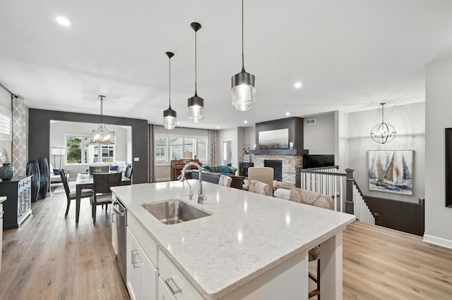 4364 Ginger Dr, Minnetrista, MN 55331 - kitchen featuring a fireplace, white cabinetry, light wood finished floors, a center island with sink, and recessed lighting