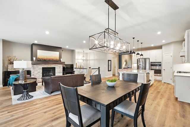 4364 Ginger Dr, Minnetrista, MN 55331 - dining room with a stone fireplace, a chandelier, recessed lighting, and light wood-type flooring