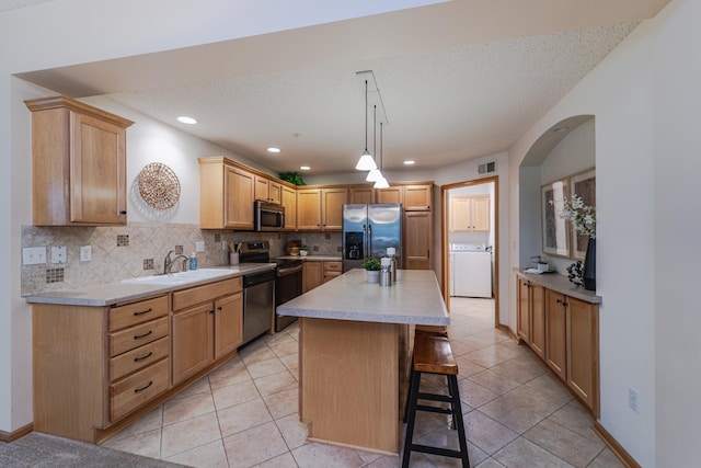625 Wesley Commons Dr Unit 36, Golden Valley, MN 55427 - kitchen with appliances with stainless steel finishes, washer / clothes dryer, backsplash, a kitchen bar, and light countertops