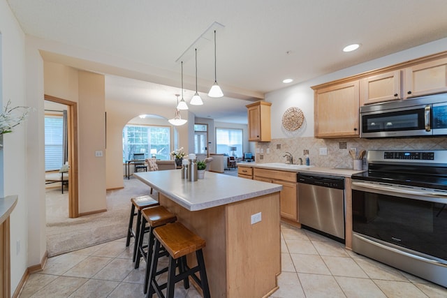 625 Wesley Commons Dr Unit 36, Golden Valley, MN 55427 - kitchen with stainless steel appliances, light brown cabinets, a kitchen island, light countertops, and light tile patterned flooring