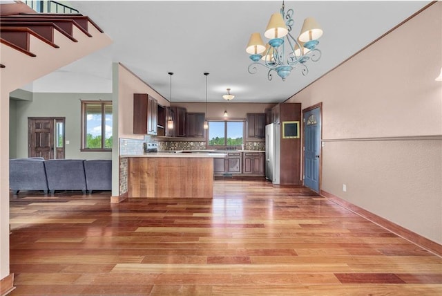 2832 130th Ave, Glenwood City, WI 54013 - kitchen with stainless steel fridge, light wood-type flooring, decorative backsplash, light countertops, and a chandelier